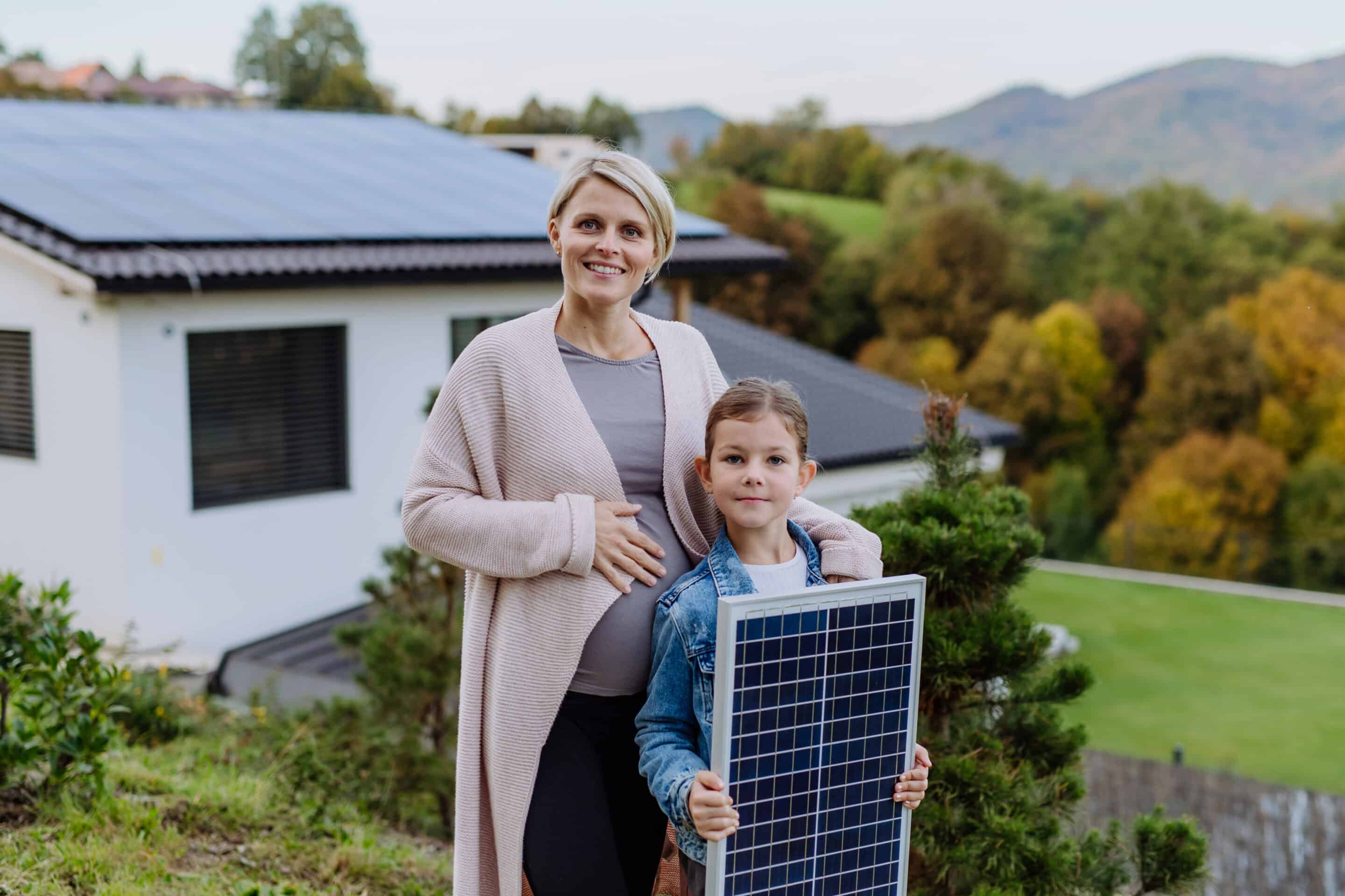 Mutter mit Sohn und einem Solarpanel vor Wohnhaus mit Photovoltaikanlage in Osnabrück